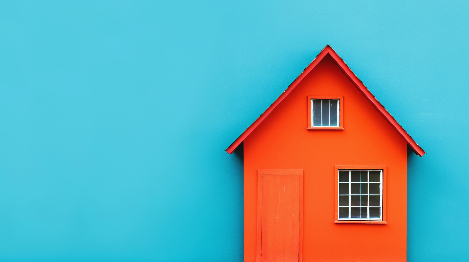 Hausmodell in orange vor blauem Hintergrund