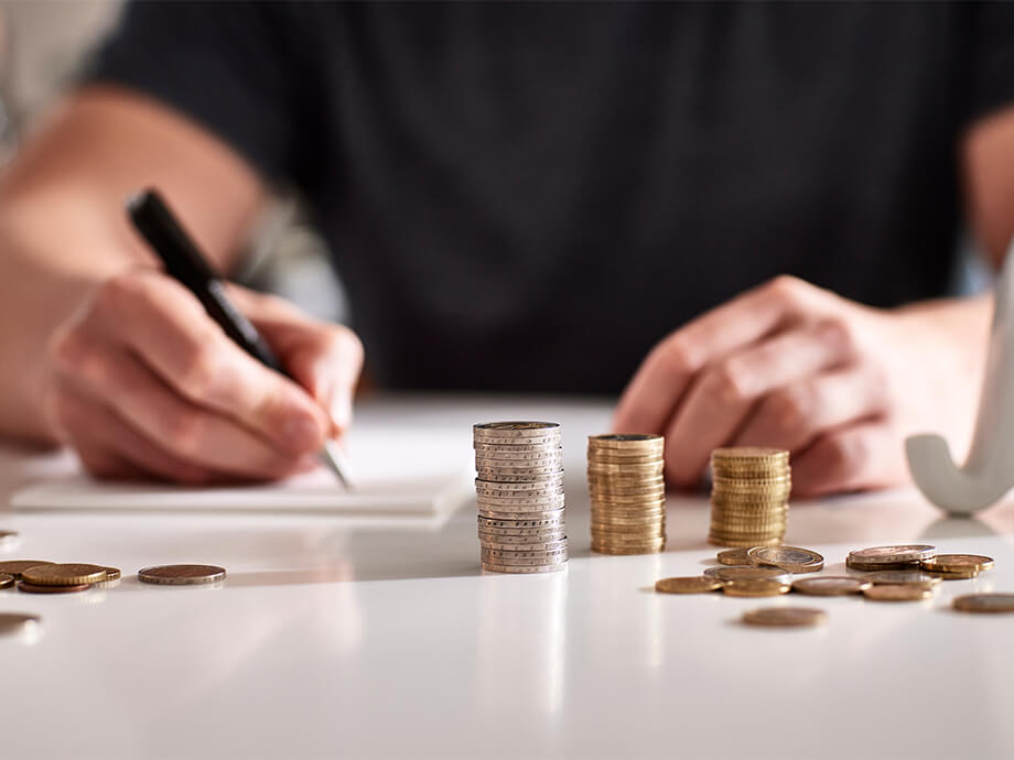 Mann mit Kugelschreiber und Münzen