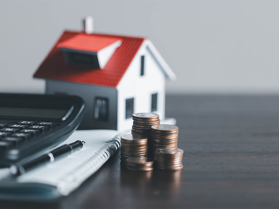 Münzen, Modellhaus und Taschenrechner