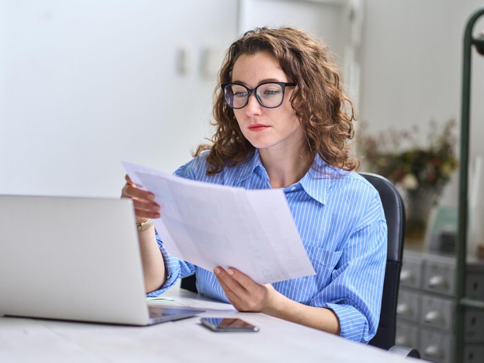 Frau mit Unterlagen am Laptop