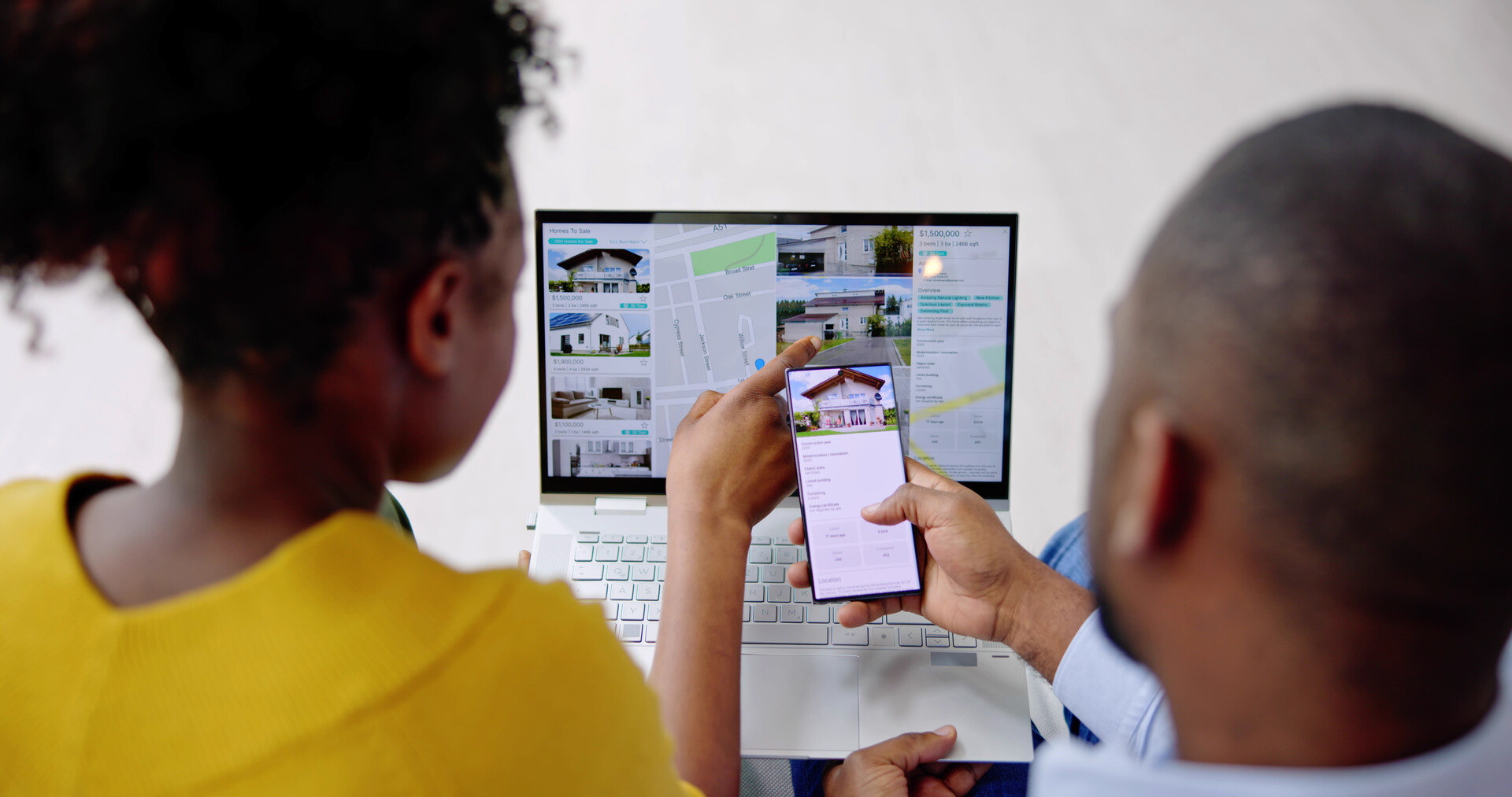 Paar sucht am Notebook und Handy nach Immobilien