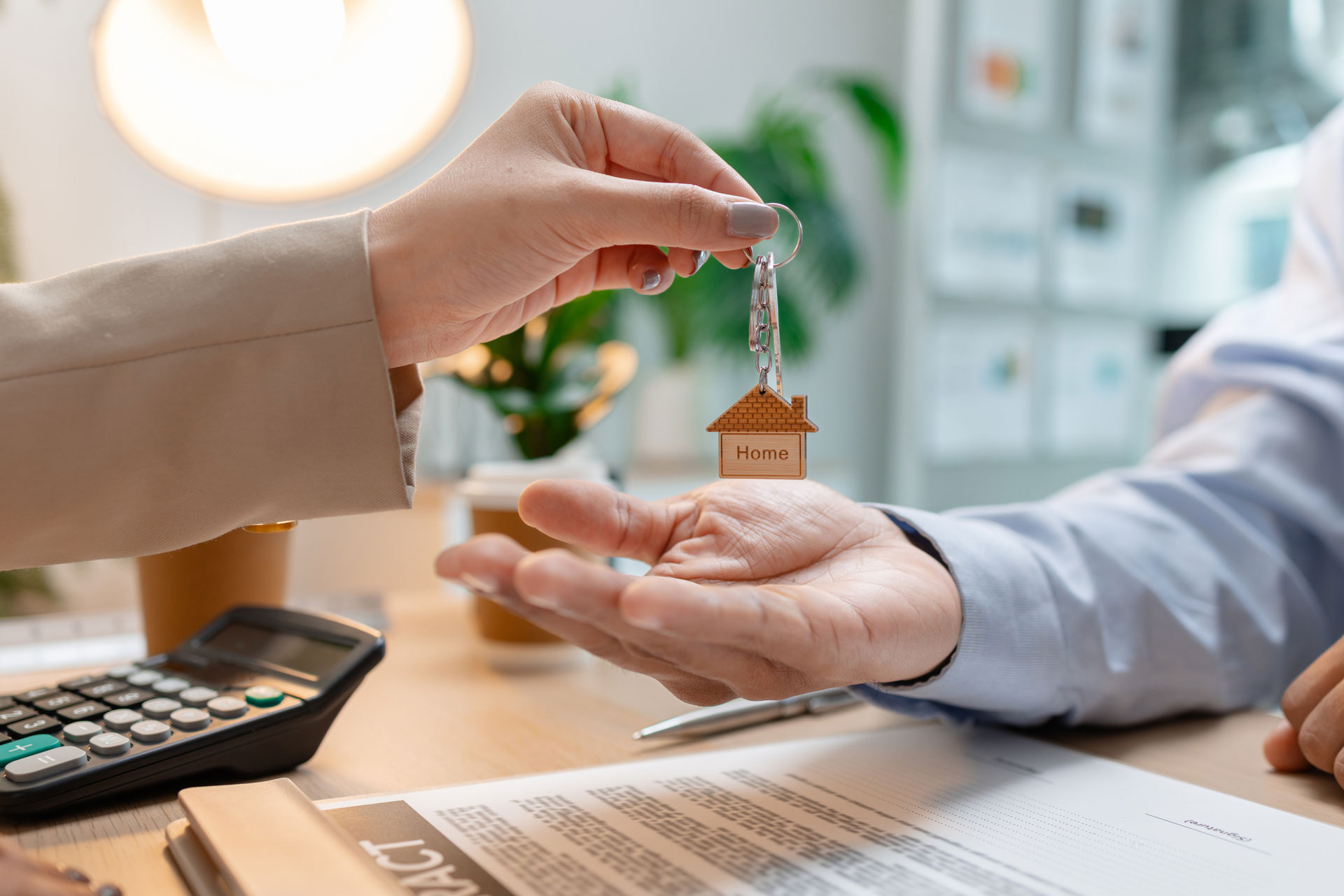 Frau übergibt Schlüssel mit Haus-Anhänger einem Mann