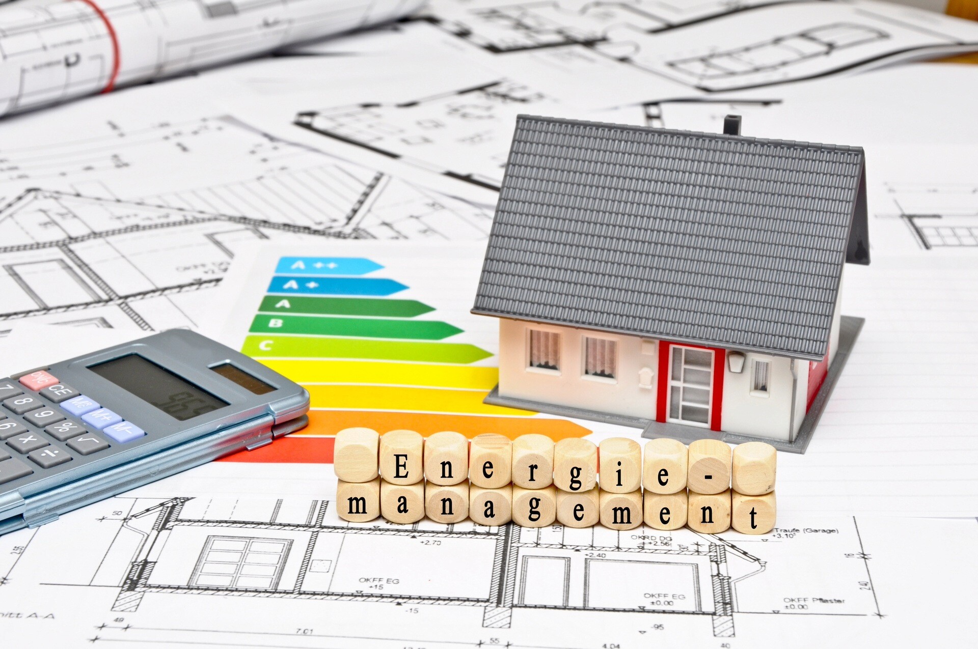 Modellhaus, Taschenrechner, Energieskala und Würfel mit der Aufschrift Energiemanagement