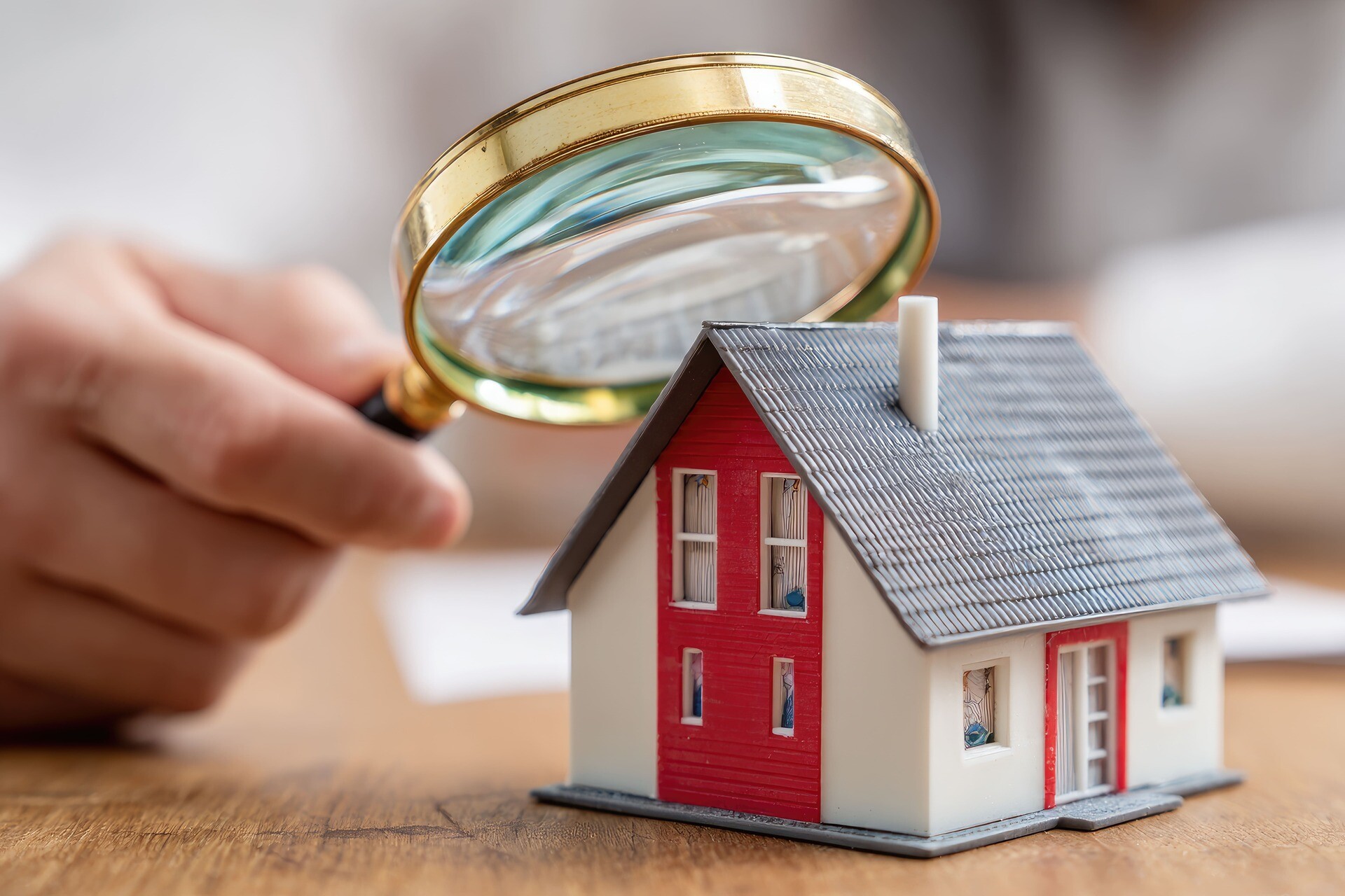 Miniaturhaus wird mit Lupe begutachtet