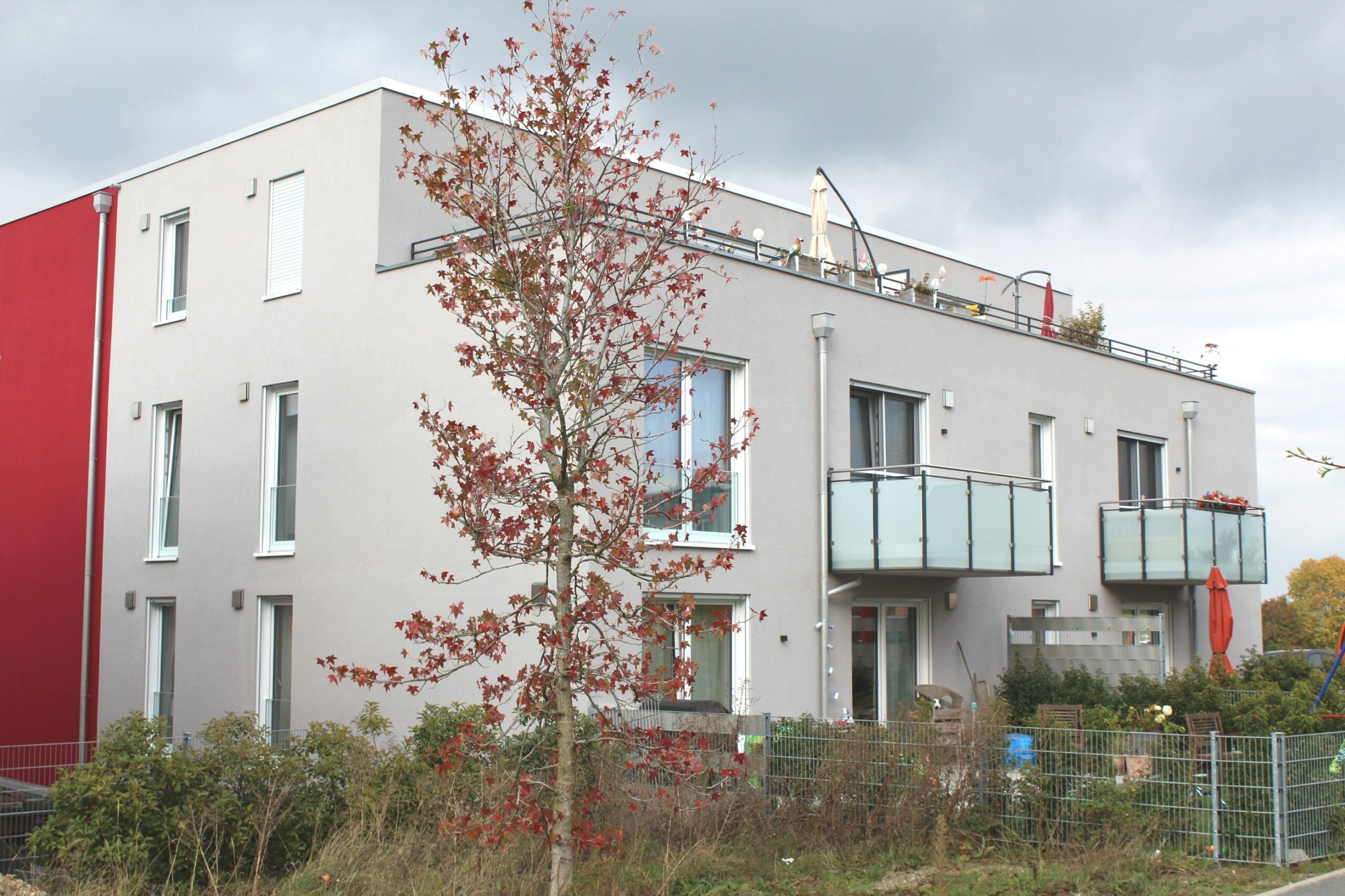 Zweistöckiges Gebäude mit Balkonen und roter Akzentwand.