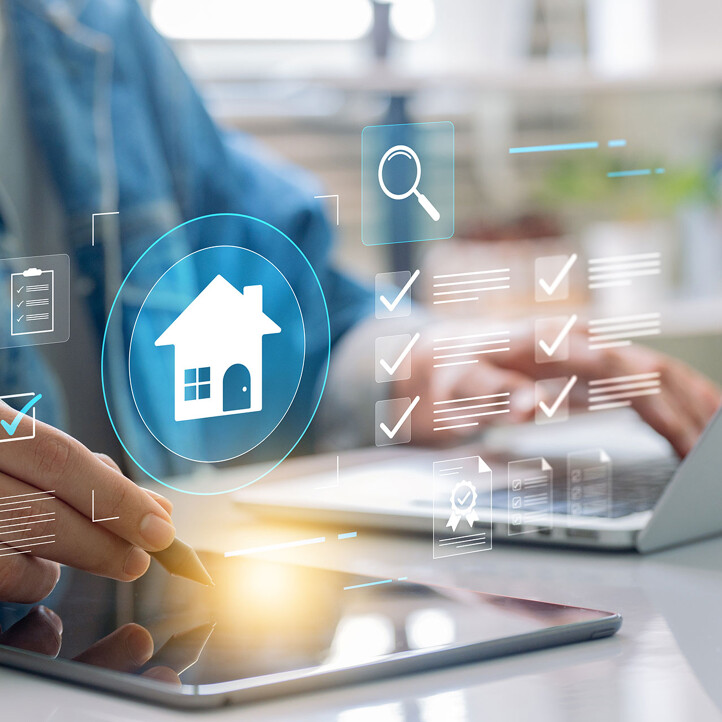 Person arbeitet am Tablet und Laptop mit Symbole für die Immobilienbewertung