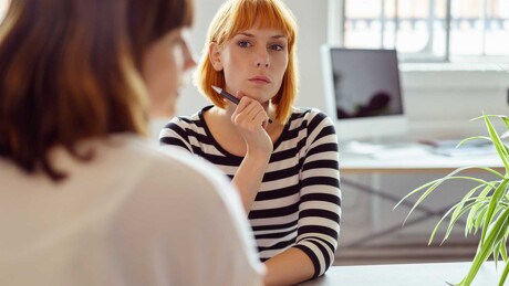 Junge Frau wird im Büro einer Maklerin zum Verkauf der geerbten Immobilie beraten