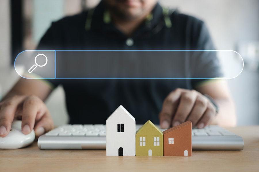 Mann mit Tastatur, Suchleiste und Modellhäusern