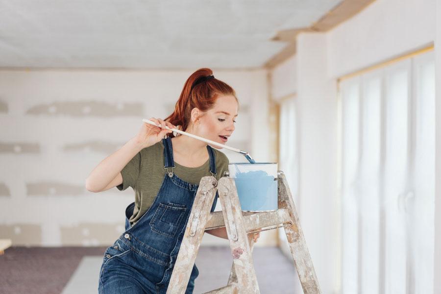 Junge Frau taucht Pinsel in Farbeimer