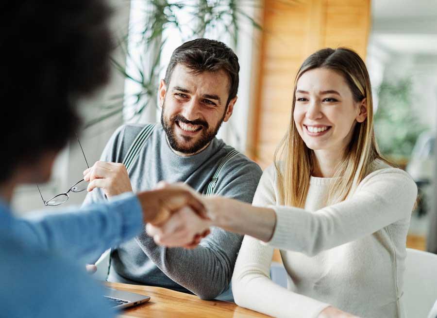 Junges Paar schüttelt Maklerin die Hand