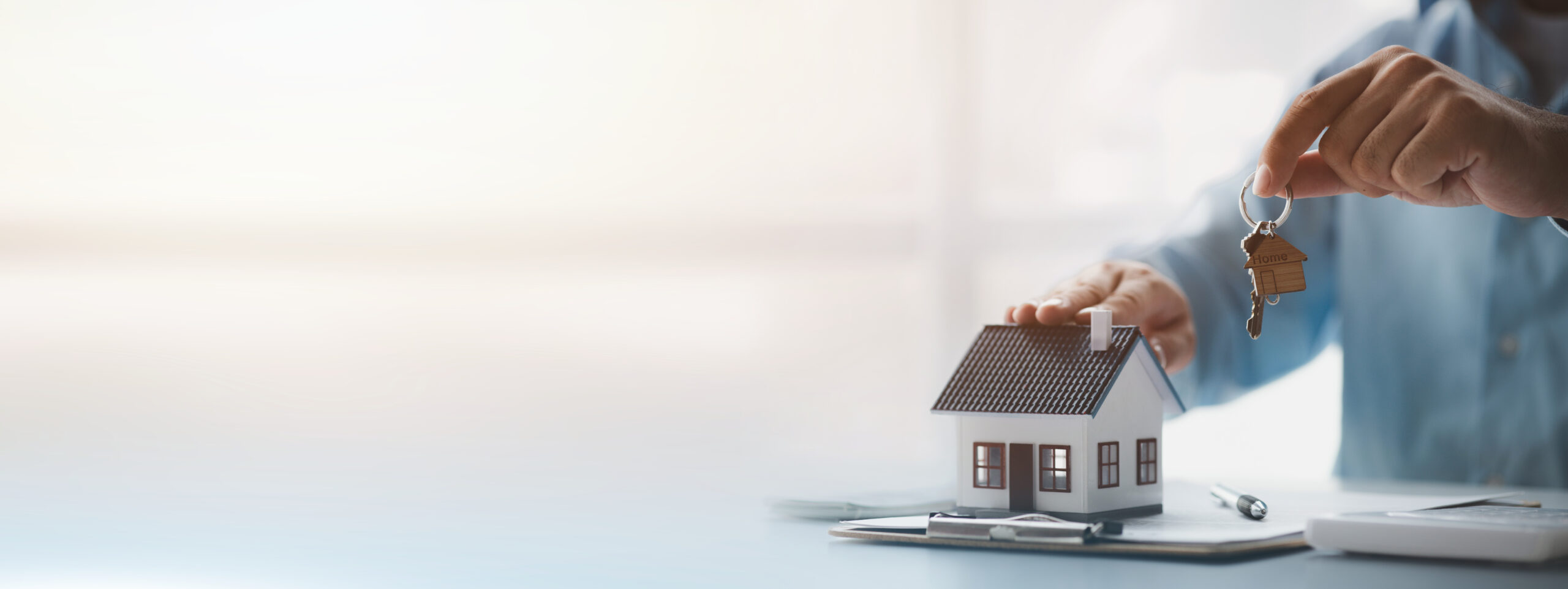 Mann hält Schlüssel und Hausmodell in Händen