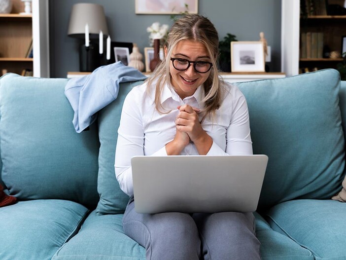 Frau mit Laptop auf Sofa