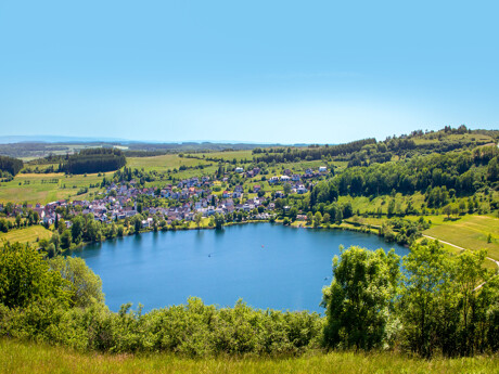 Kleinstadt an einem runden See mit Feldern und Bäumen.