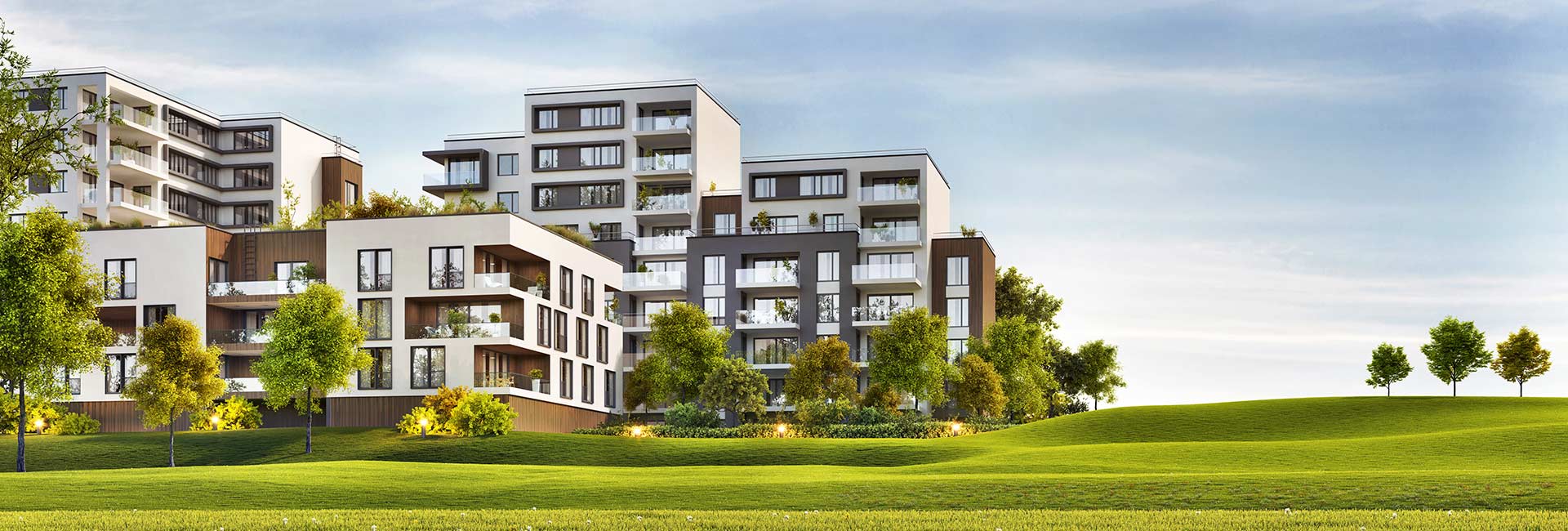 Mehrfamilienhäuser mit Balkonen, grünen Rasenflächen und Bäumen.