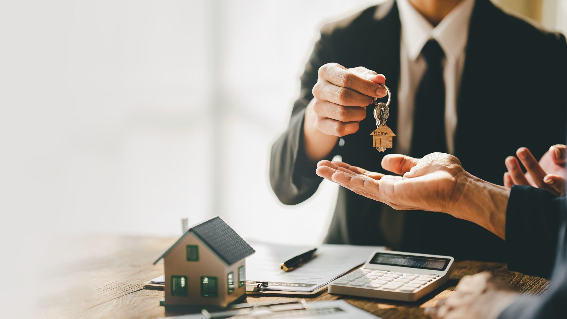 Eine Person reicht einen Hausschlüssel an eine weitere Person