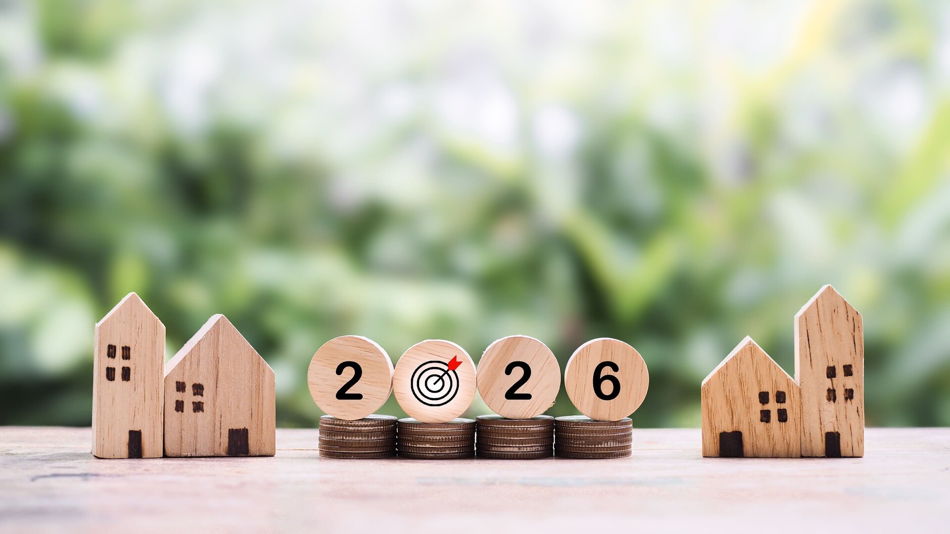 Modellhäuser, Münzstapel und 2026 auf Holzscheiben
