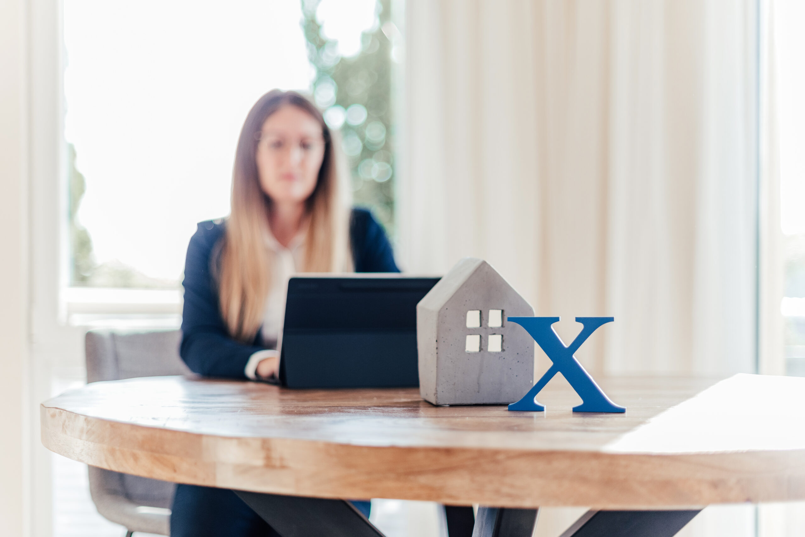 Unternehmenssymbol und Hausmodell vor Mitarbeiterin