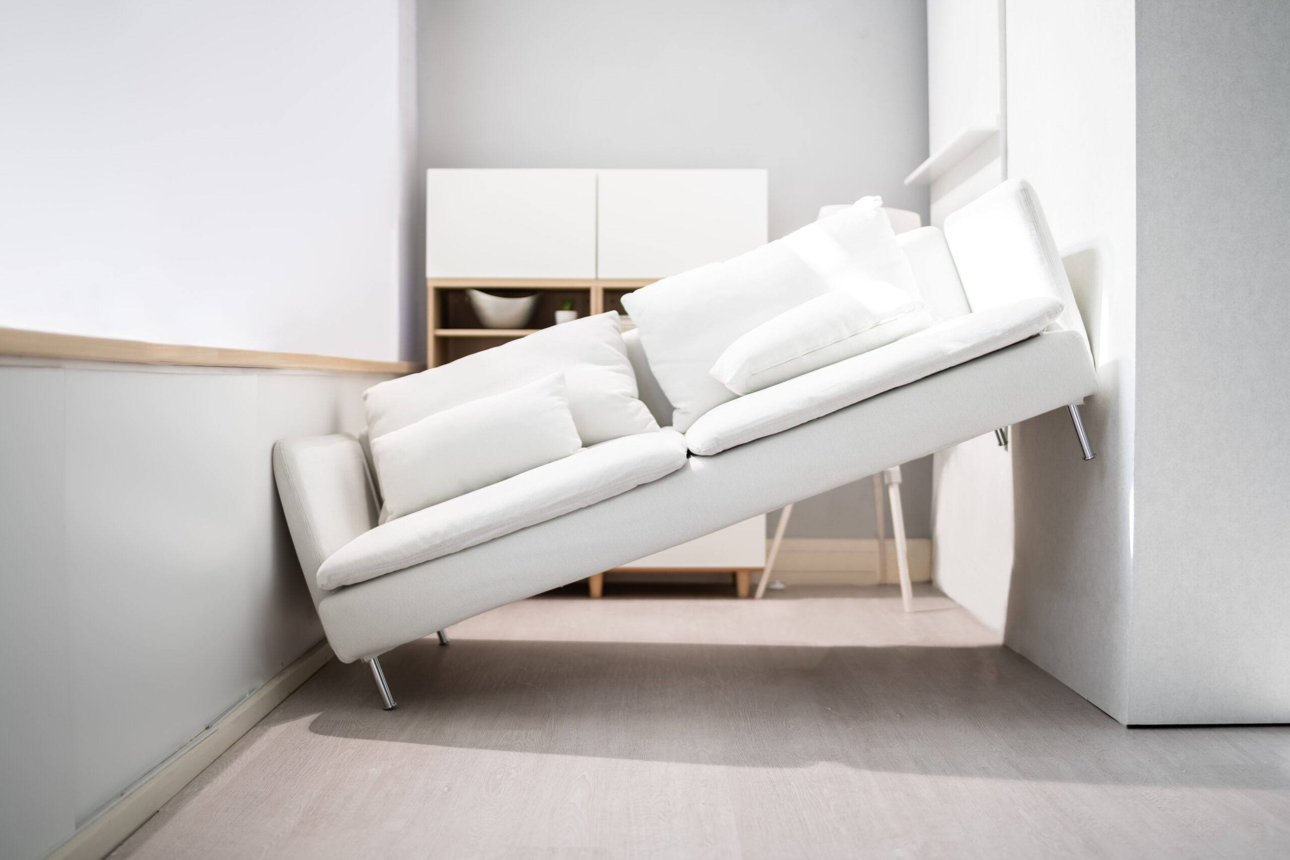 Weiße Couch steht schräg an der Wand in modernem Wohnzimmer.