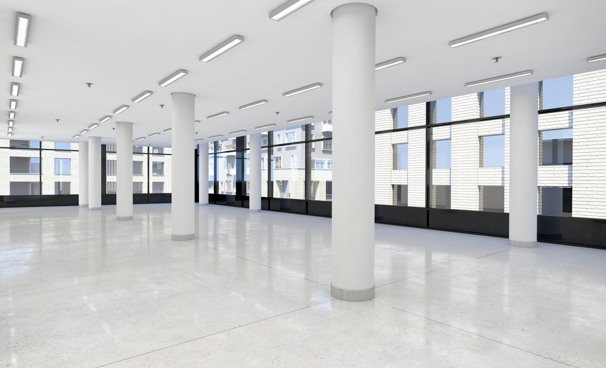 Modernes Büro mit weißen Säulen, großen Fenstern, polierten Böden.