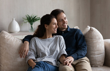 Ein Paar sitzt eng beieinander auf dem Sofa und lächelt.