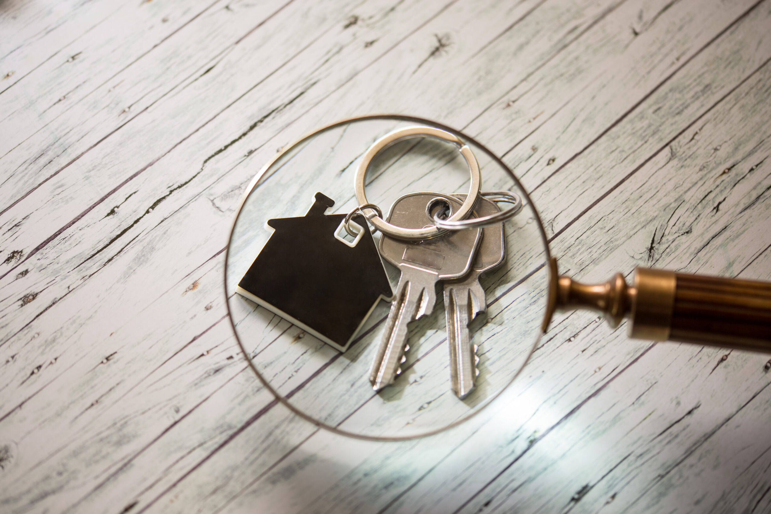 Lupe über hausförmigem Schlüsselanhänger und zwei Schlüsseln.