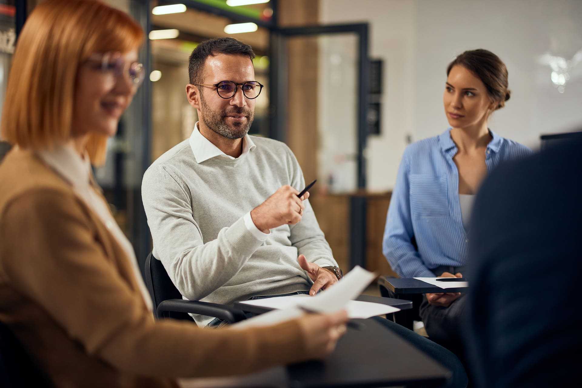 Verkäufer mit Unterlagen und Kugelschreiber im Gespräch mit zwei Kaufinteressenten.