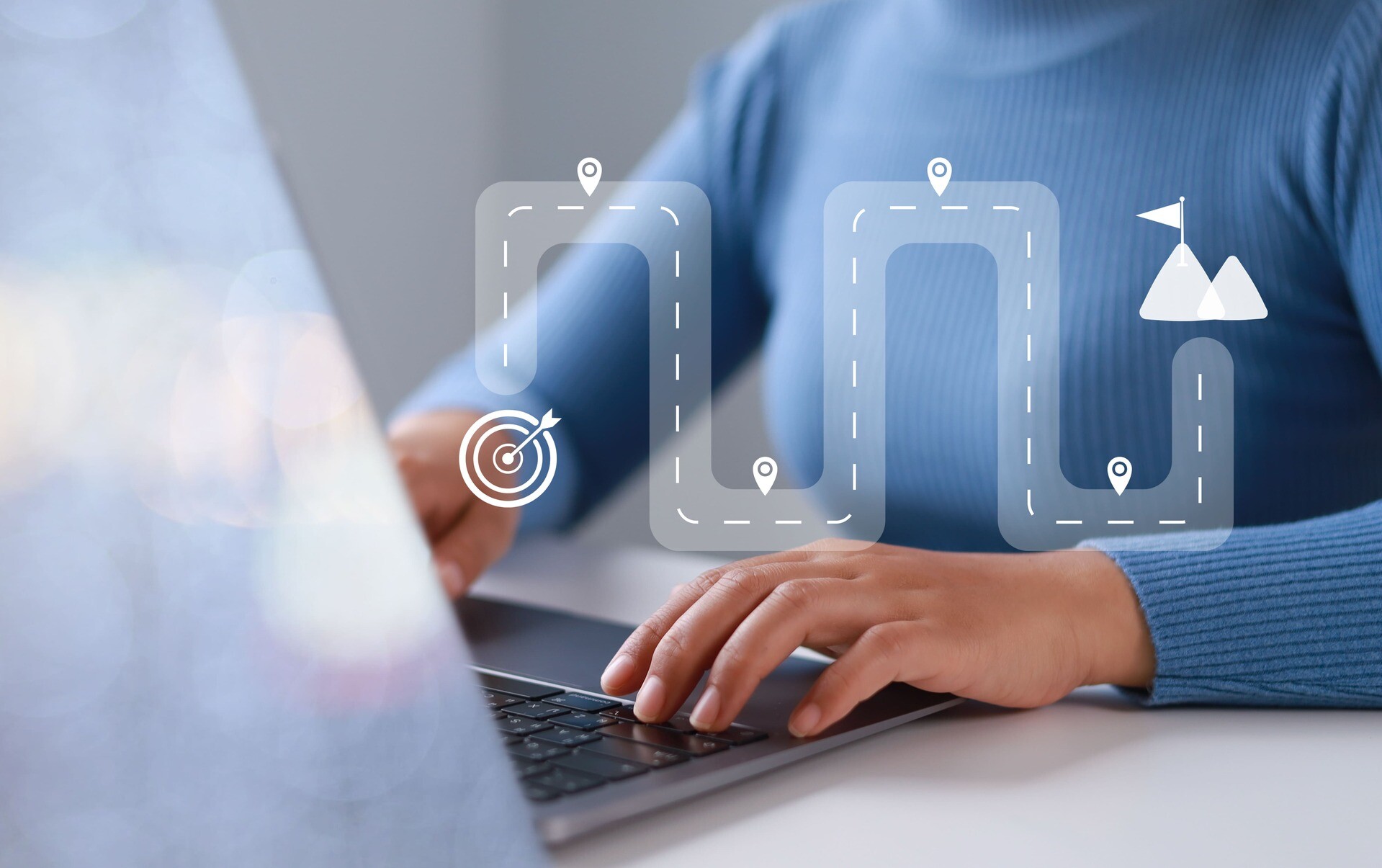 Person sitzt vor einem Laptop, davor eine grafische Darstellung eines Weges
