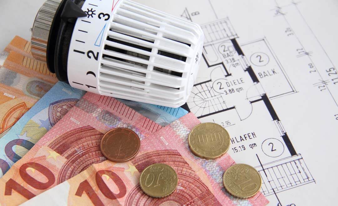 Eurogeld, Thermostat und Grundriss symbolisieren Energiekosten.