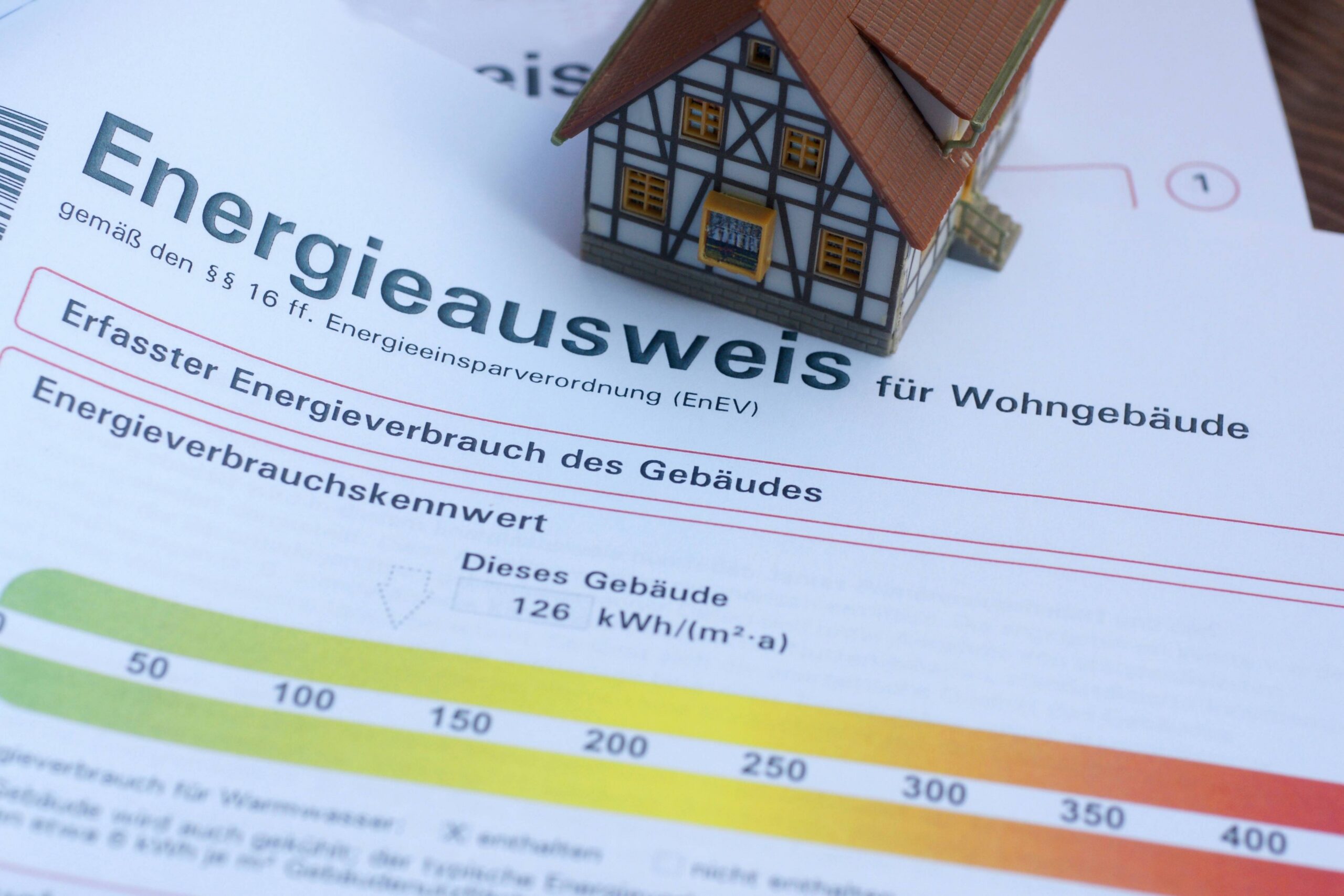 Modellhaus auf einem Energieausweis für ein Wohngebäude mit einem Verbrauchskennwert von 126 kWh.