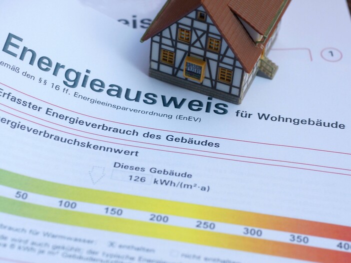 Modellhaus auf einem Energieausweis für ein Wohngebäude mit einem Verbrauchskennwert von 126 kWh.