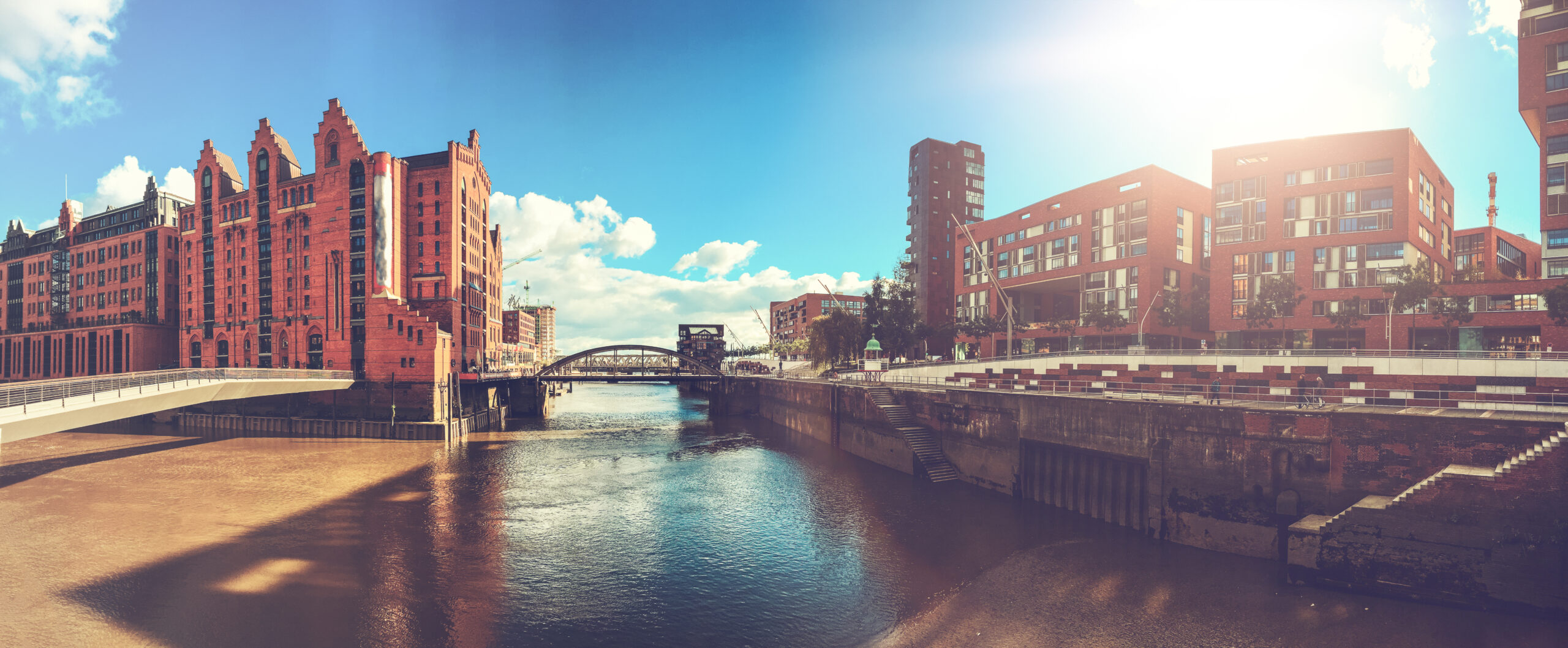 Riverside-Stadt mit roten Backsteinbauten, Brücken und blauem Himmel.
