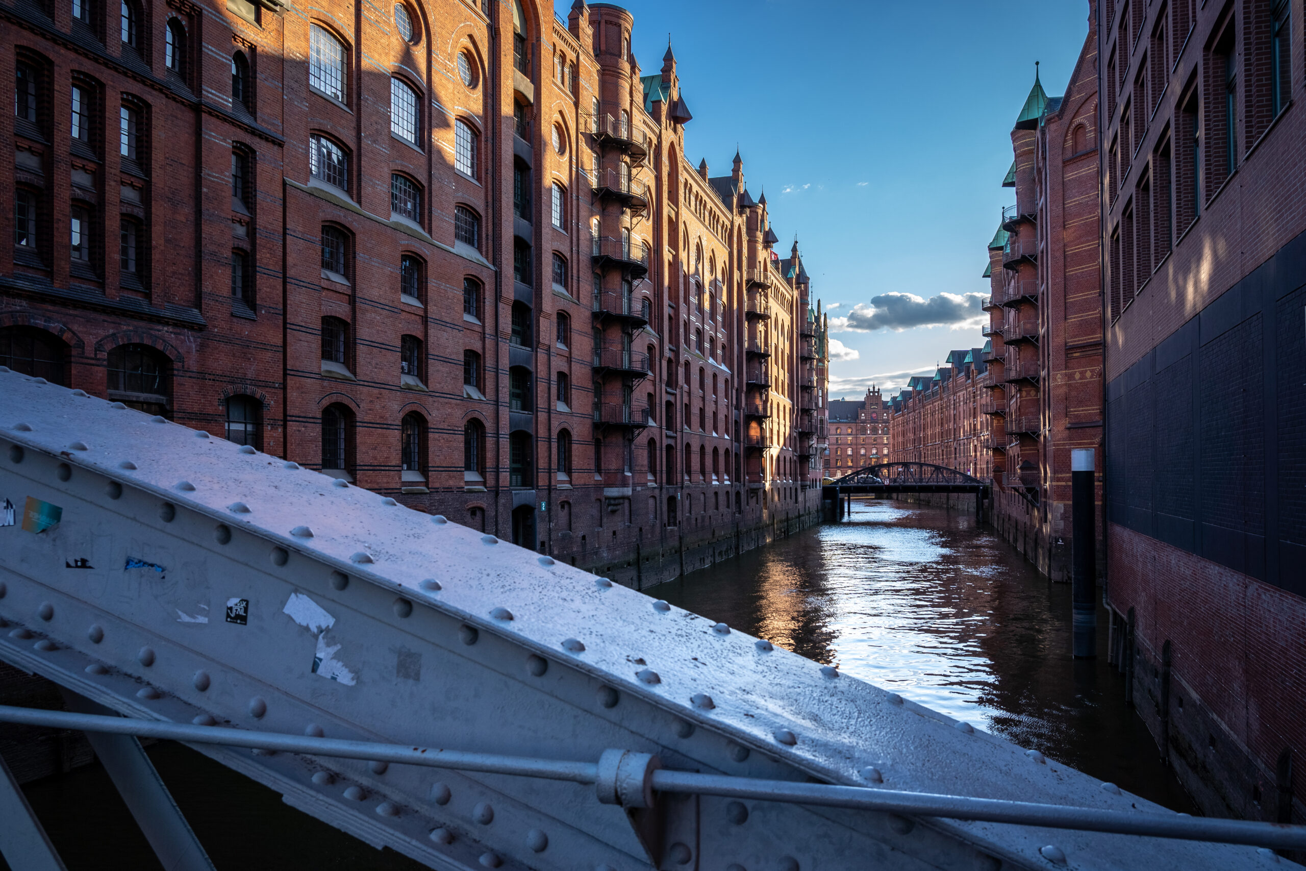 Kanal zwischen hohen Backsteingebäuden, gesehen hinter Metall.