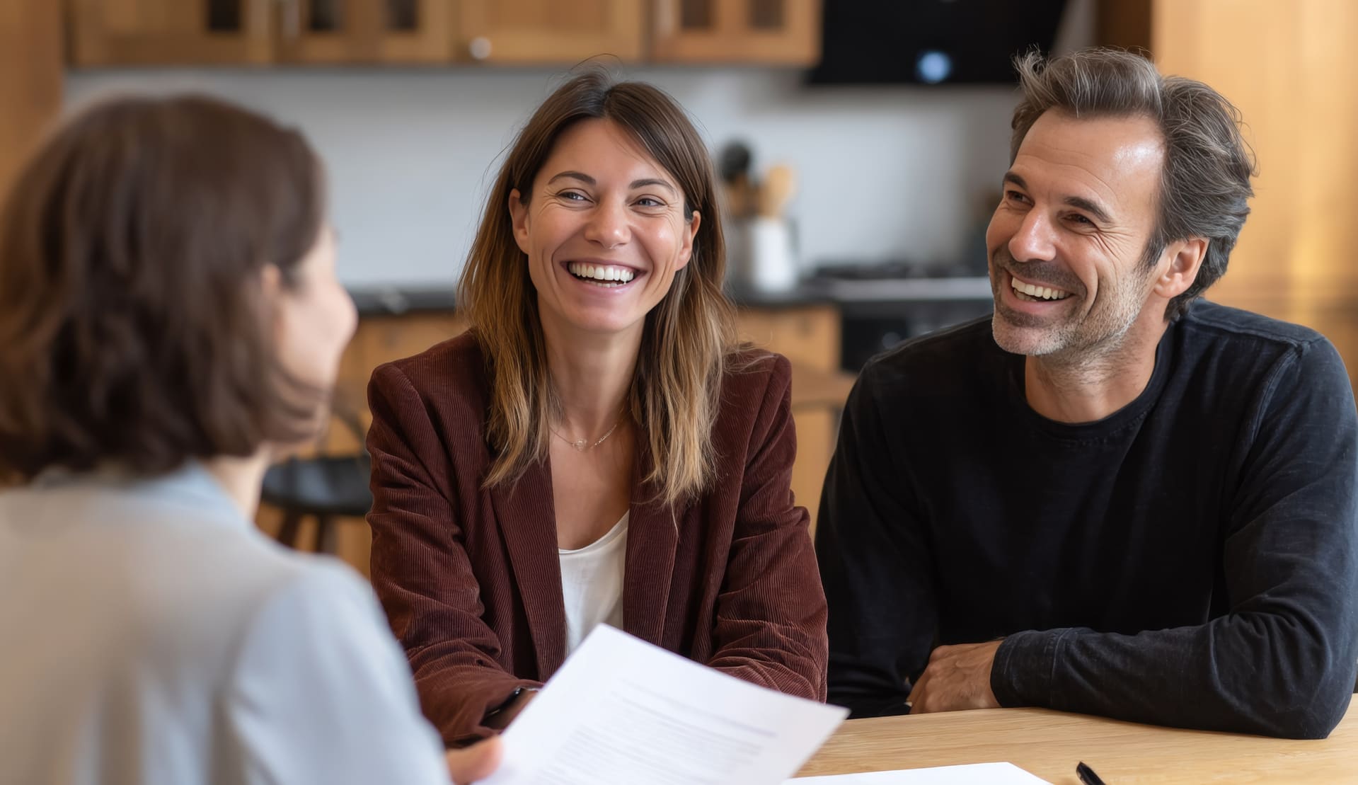 Maklerin sitzt mit Kunden in moderner Küche und bespricht Details zum Immobilienkauf.