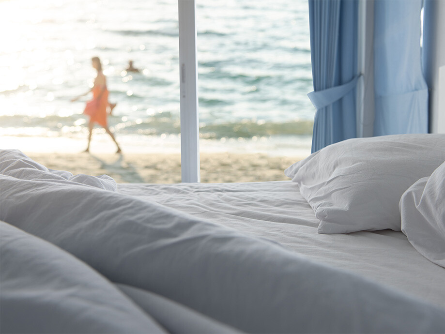 Ungemachtes Bett mit Blick auf den Strand und das Meer in Griechenland