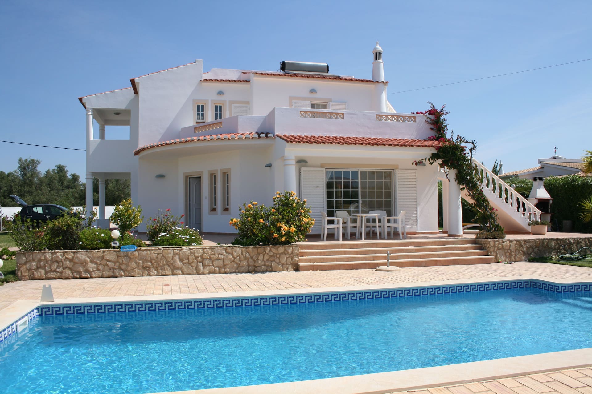 Weißes zweistöckiges Haus mit Pool, Patio und Außentreppe
