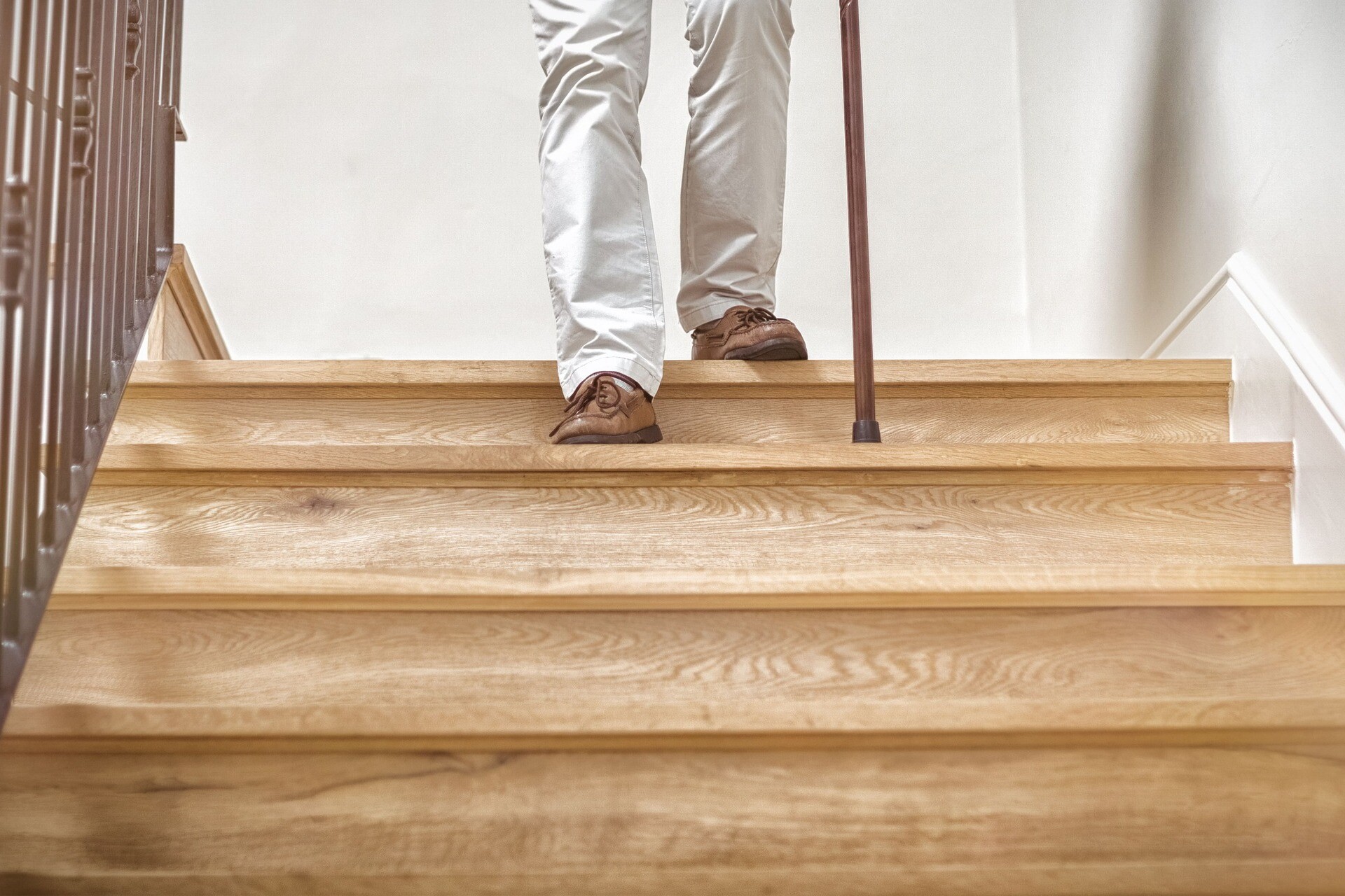 Älterer Herr mit Stock geht Treppe hinunter