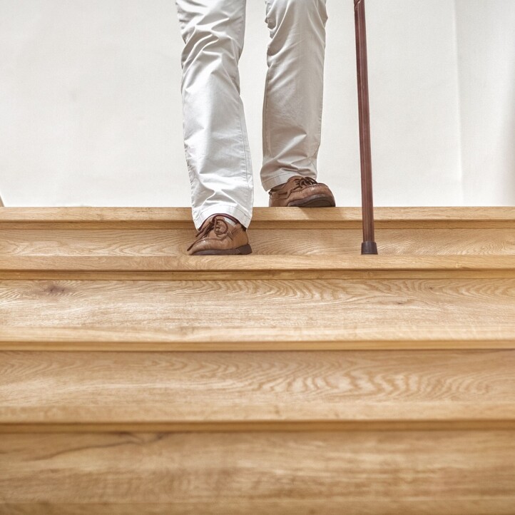 Älterer Herr mit Stock geht Treppe hinunter
