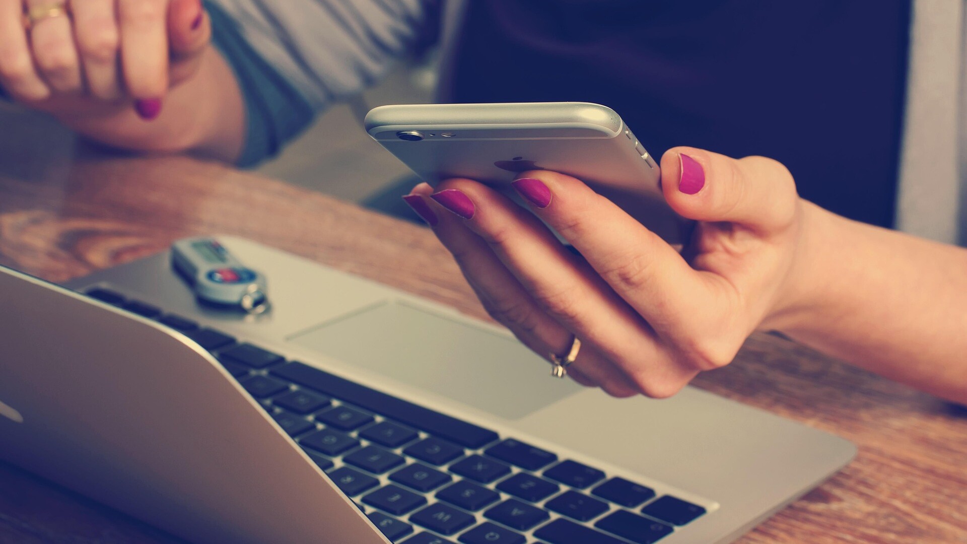 Eine Person mit lackierten Fingernägeln hält ein iPhone in der Hand