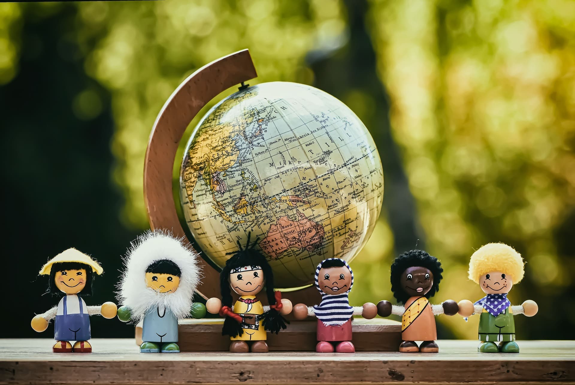 Mehrere detaillierte Holzfiguren stehen vor einem Globus