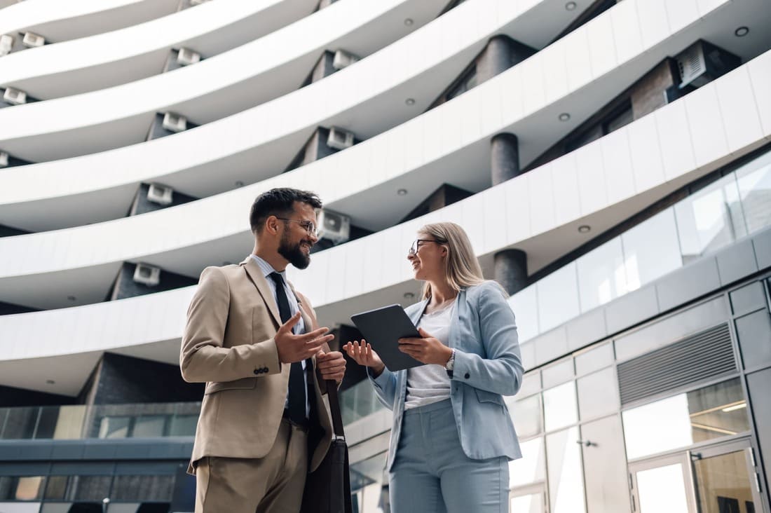 Zwei Immobilienmakler sprechen vor einem Bürogebäude