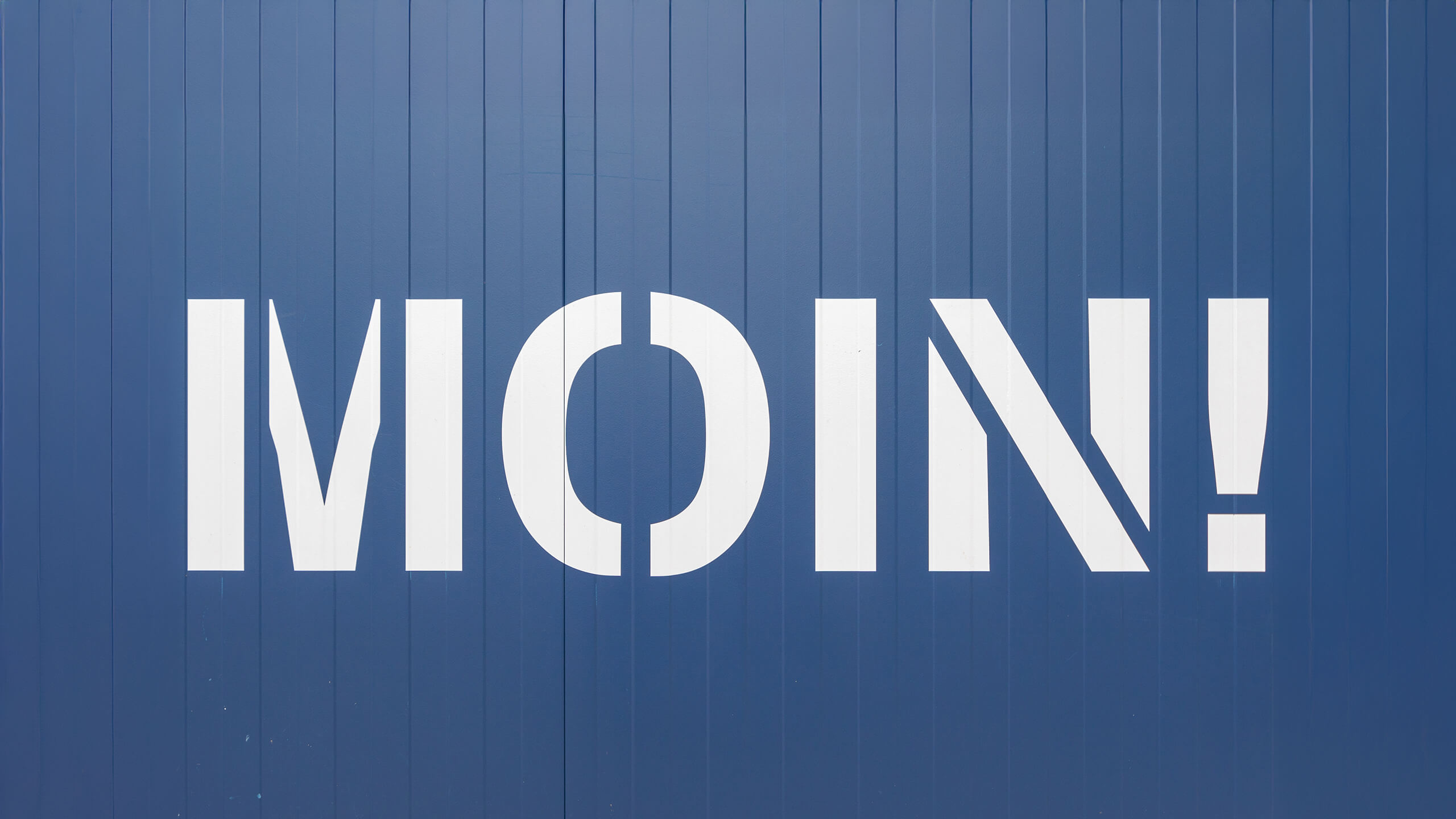 Weißes "MOIN!" auf einer blauen Wand