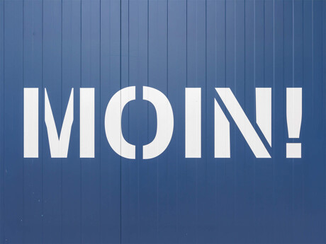 Weißes "MOIN!" auf einer blauen Wand