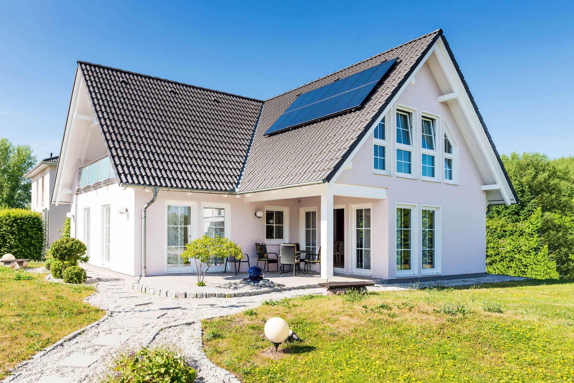 Modernes weißes Haus, große Fenster, Schrägdach, Sonnenkollektoren.