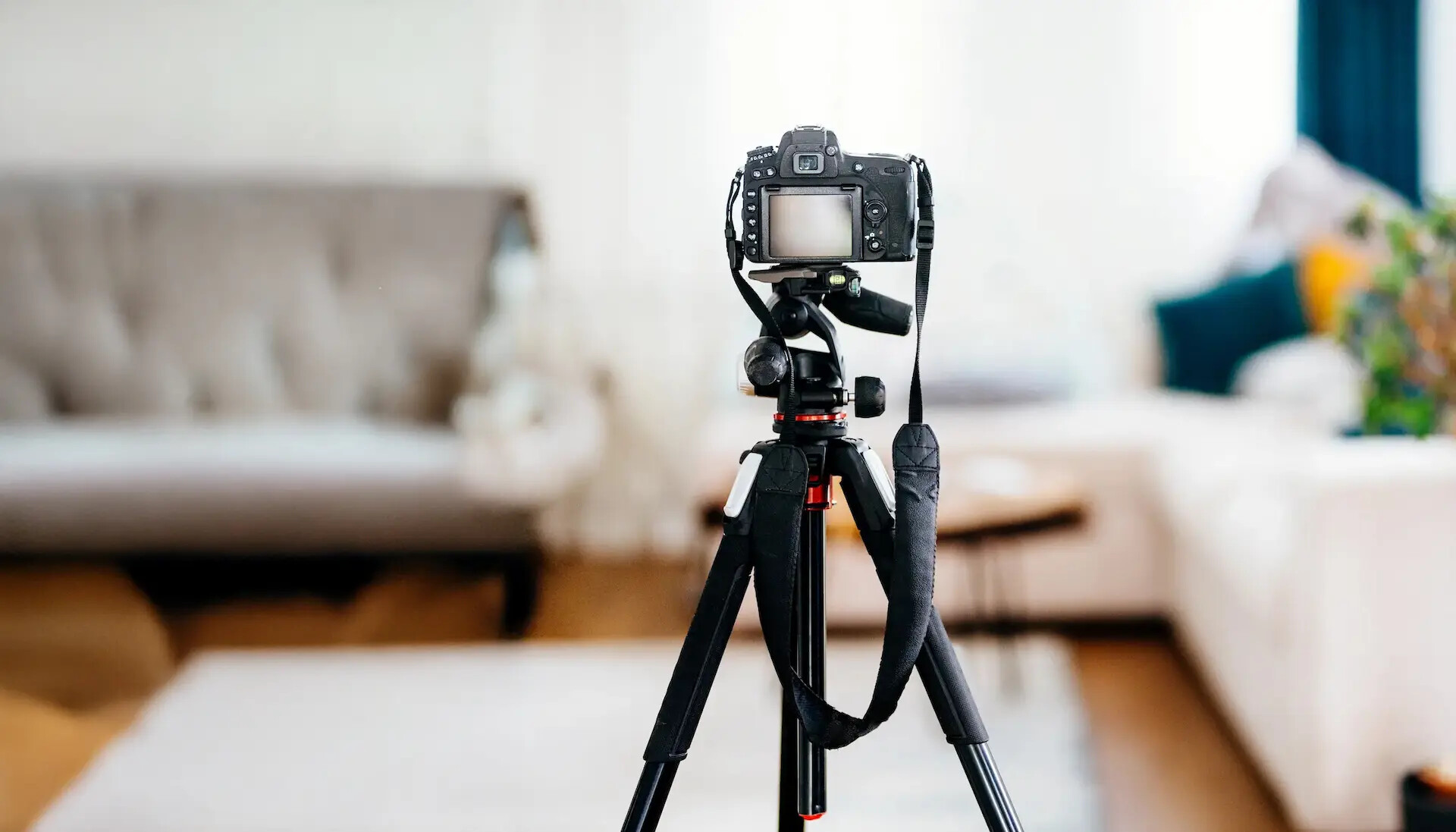 Kamera auf Stativ im Wohnzimmer mit Sofa und sanfter Beleuchtung.