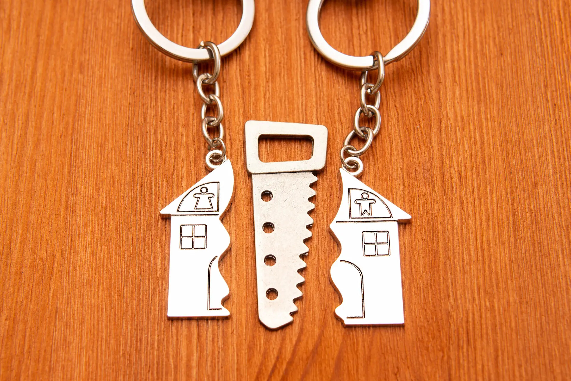 Zwei Schlüsselanhänger mit Haus- und Schlüsselmotiv auf Holz.