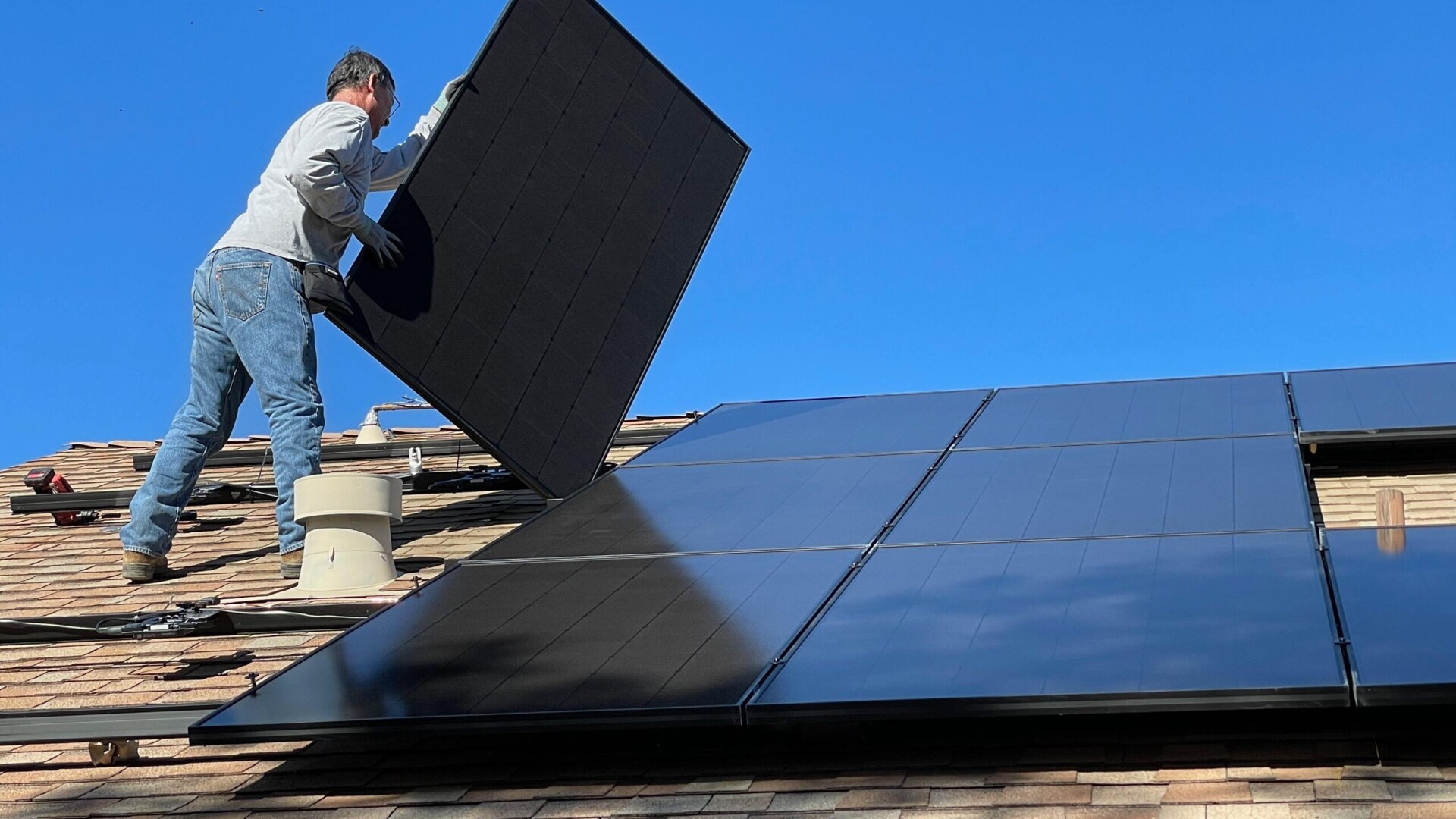 Ein Handwerker installiert Solarpaneele auf einem Dach
