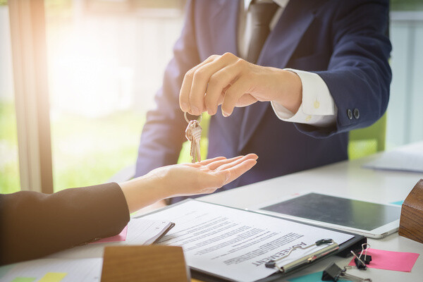Ein Immobilienmakler übergibt den Schlüssel für eine Immobilie an die neuen Eigentümer