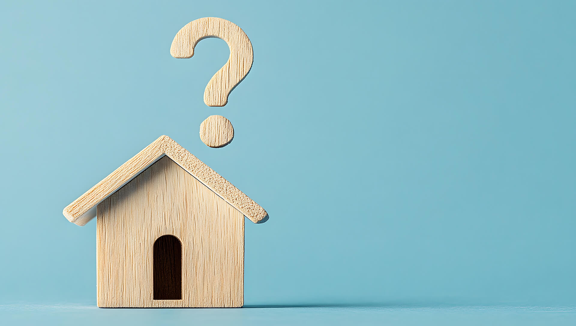 Holzhaus mit Fragezeichen darüber, blauer Hintergrund.