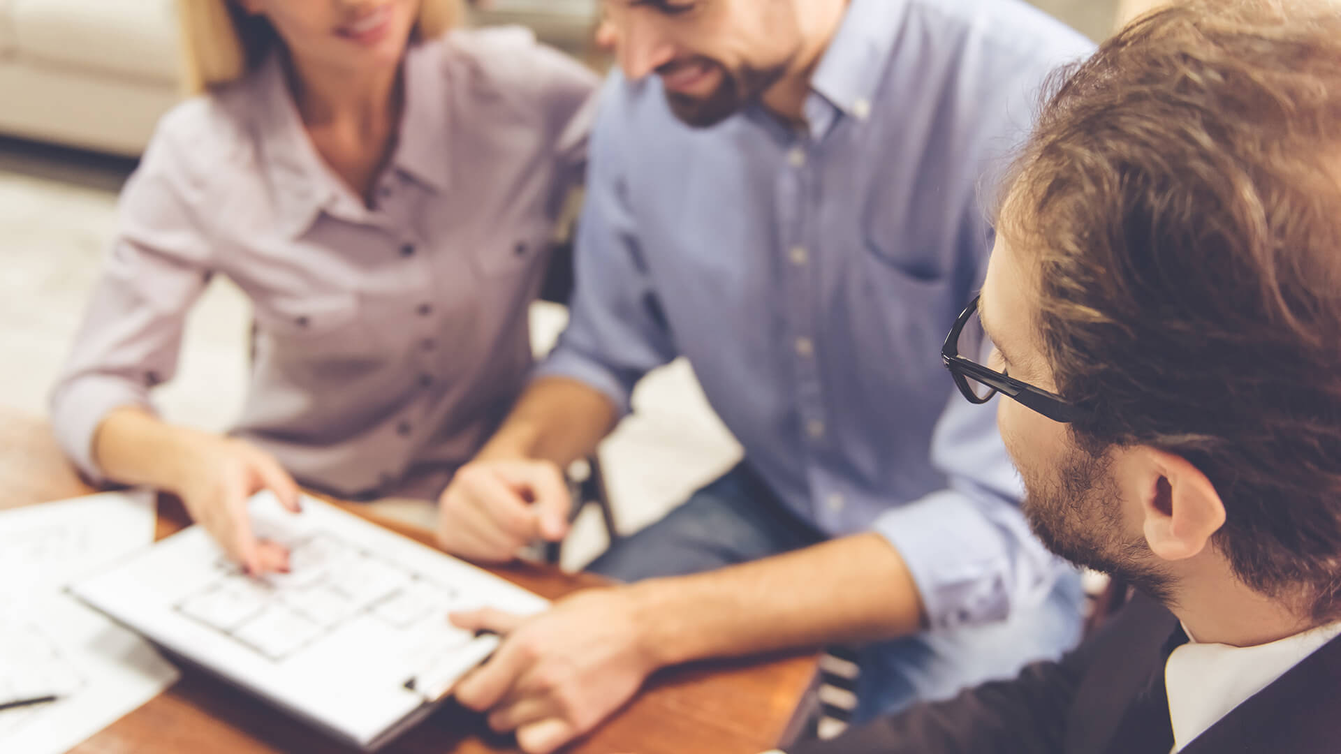 Drei Personen besprechen gemeinsam einen Bauplan am Tisch.