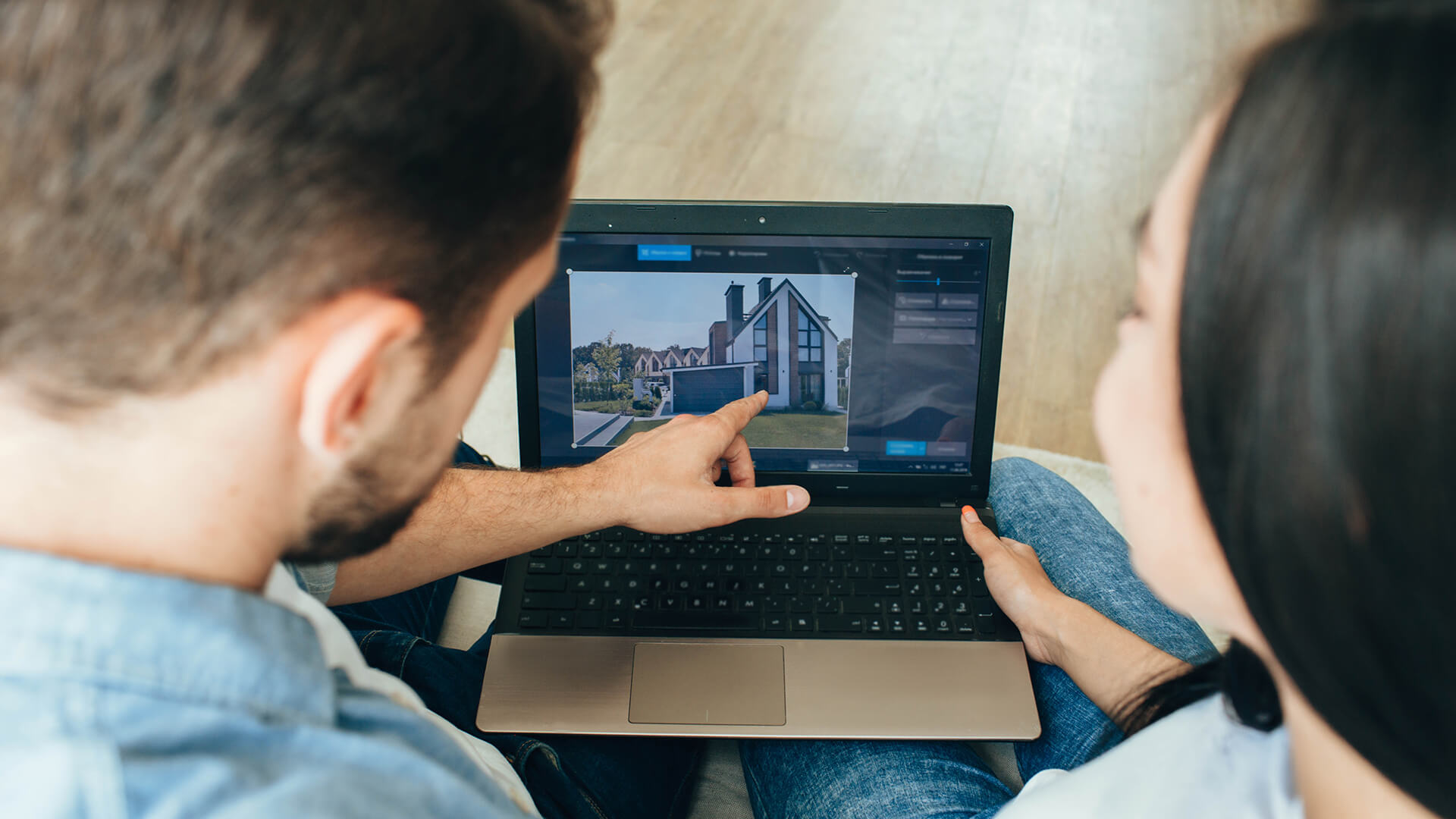 Zwei Personen betrachten am Laptop ein modernes Hausfoto